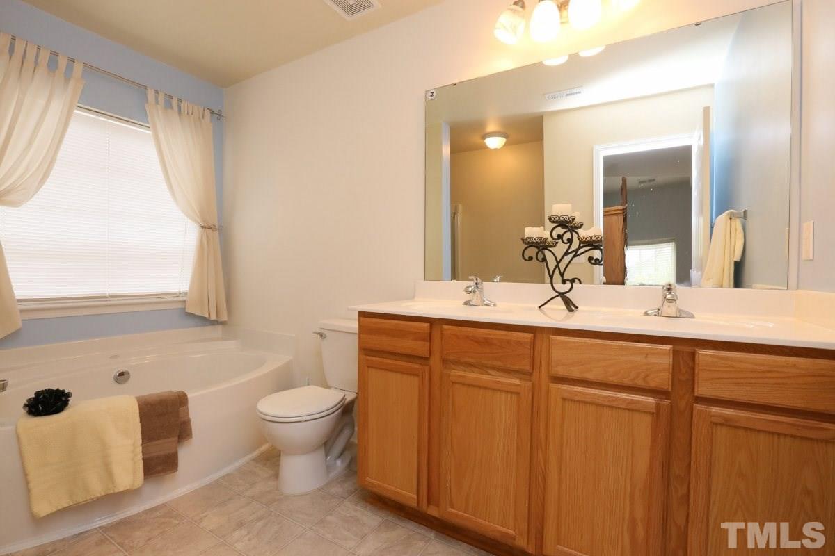 5944 Ricker Road Raleigh, NC 27610 - Photo 17 of 25 a bathroom with a double vanity sink toilet and mirror