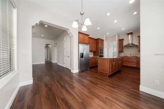 a kitchen with stainless steel appliances granite countertop a refrigerator a sink dishwasher a oven with wooden cabinets and wooden floor