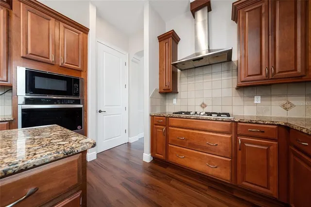 a large kitchen with stainless steel appliances wooden floors and wooden cabinets