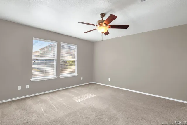 an empty room with a window and a ceiling fan