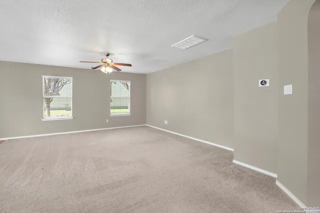 a view of an empty room with a window and a kitchen