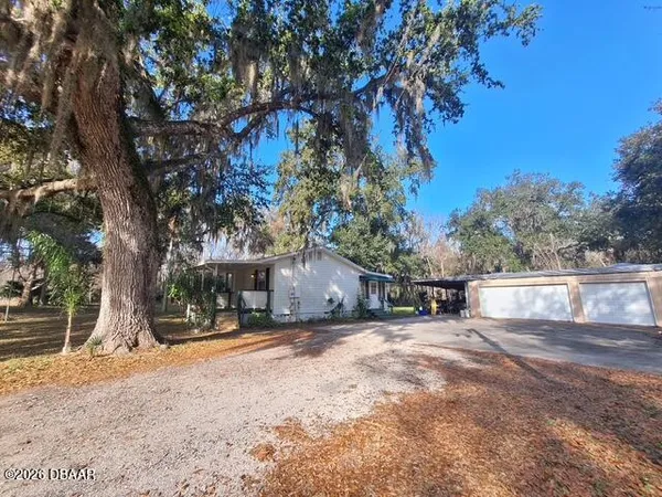a view of a house with a large tree and a yard