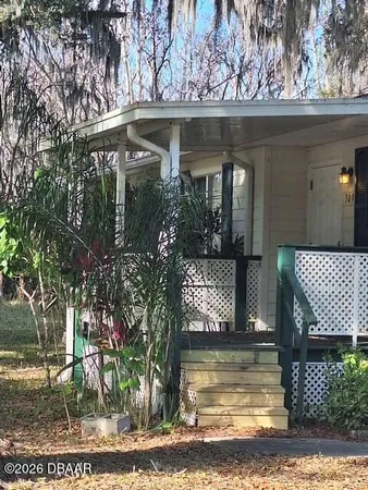 a view of a small yard in front of a house with large trees