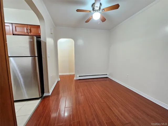 a view of a room with wooden floor and a refrigerator