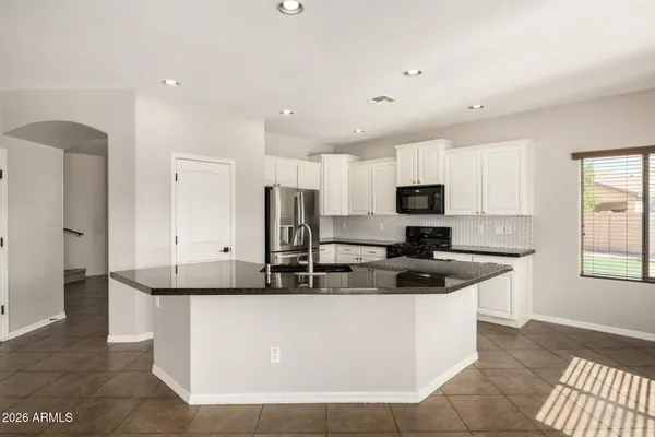 a kitchen with stainless steel appliances granite countertop a sink a stove a refrigerator a microwave and cabinets