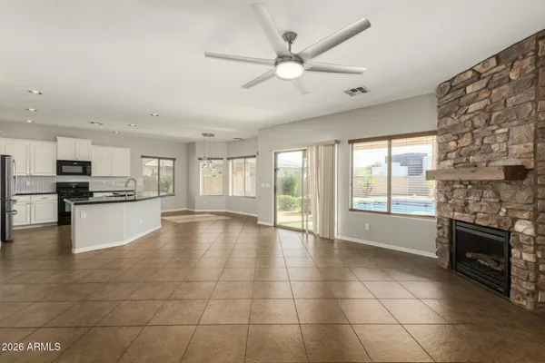 a view of an empty room with kitchen and window