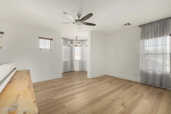 an empty room with wooden floor closet and windows