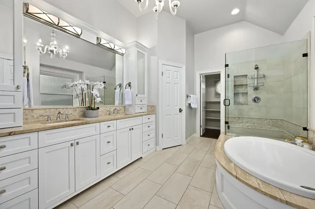a bathroom with a granite countertop sink a large mirror and a bathtub