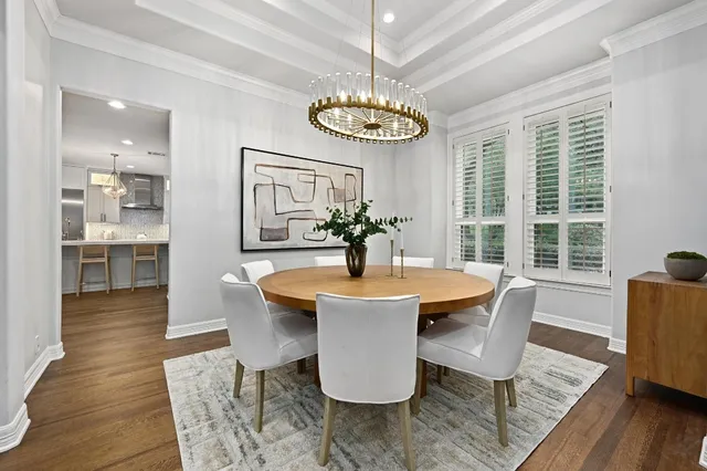 a dining room with wooden floor a chandelier a wooden table and chairs