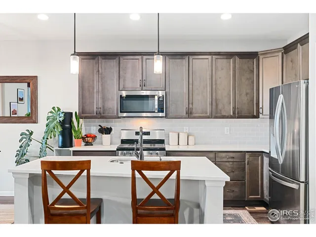 a kitchen with stainless steel appliances kitchen island granite countertop a refrigerator a sink a stove with wooden cabinets