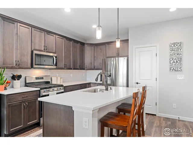 a kitchen with a stove a sink a microwave a refrigerator cabinets and dining table