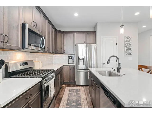 a kitchen with stainless steel appliances a sink a stove a microwave a sink a refrigerator and cabinets