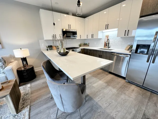 a kitchen with kitchen island a stove a sink a microwave a refrigerator and cabinets