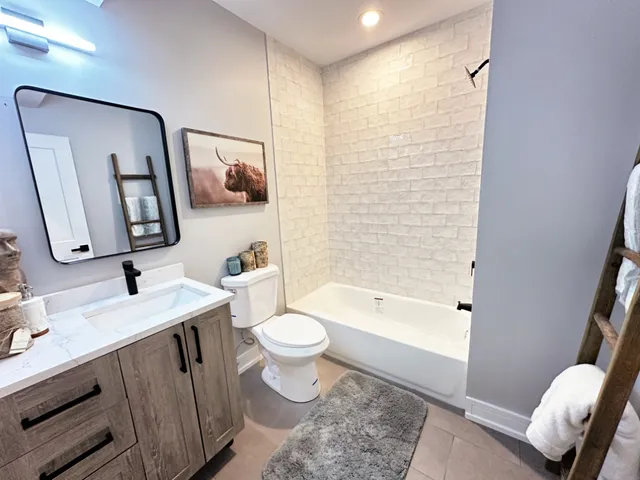 a bathroom with a toilet a sink a tub and mirror