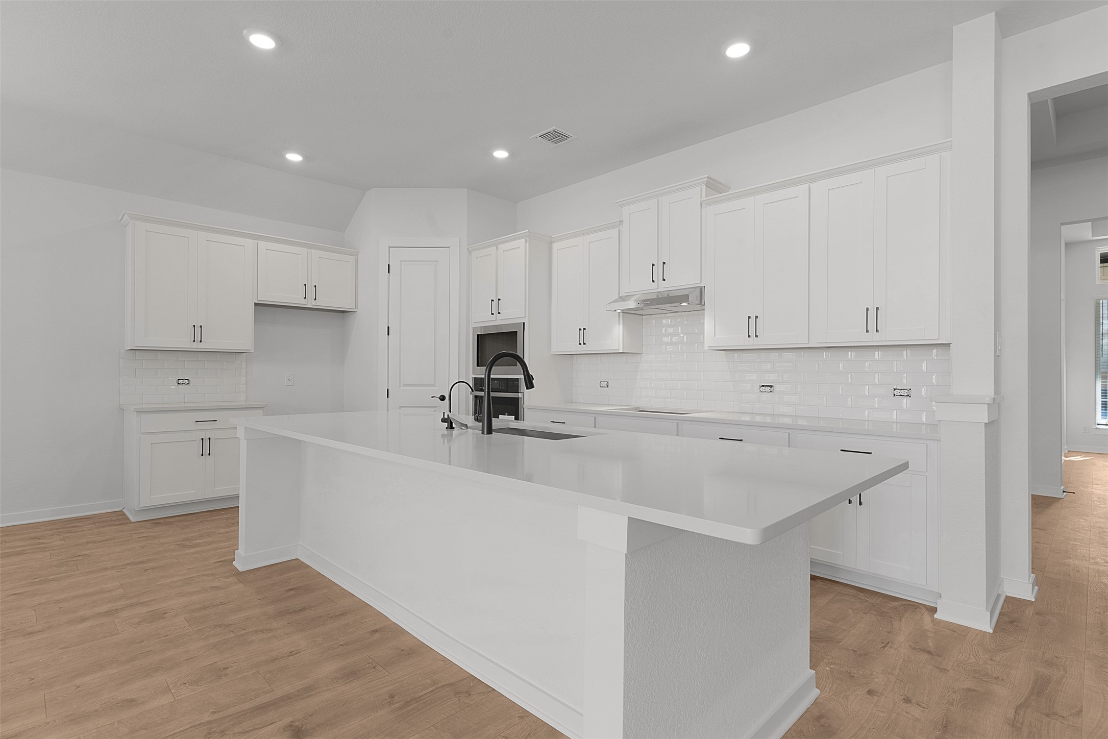 328 Ridgewell Loop Georgetown, TX 78633 - Photo 13 of 28 Kitchen with backsplash, white cabinetry, a kitchen island with sink, light wood finished floors, and recessed lighting