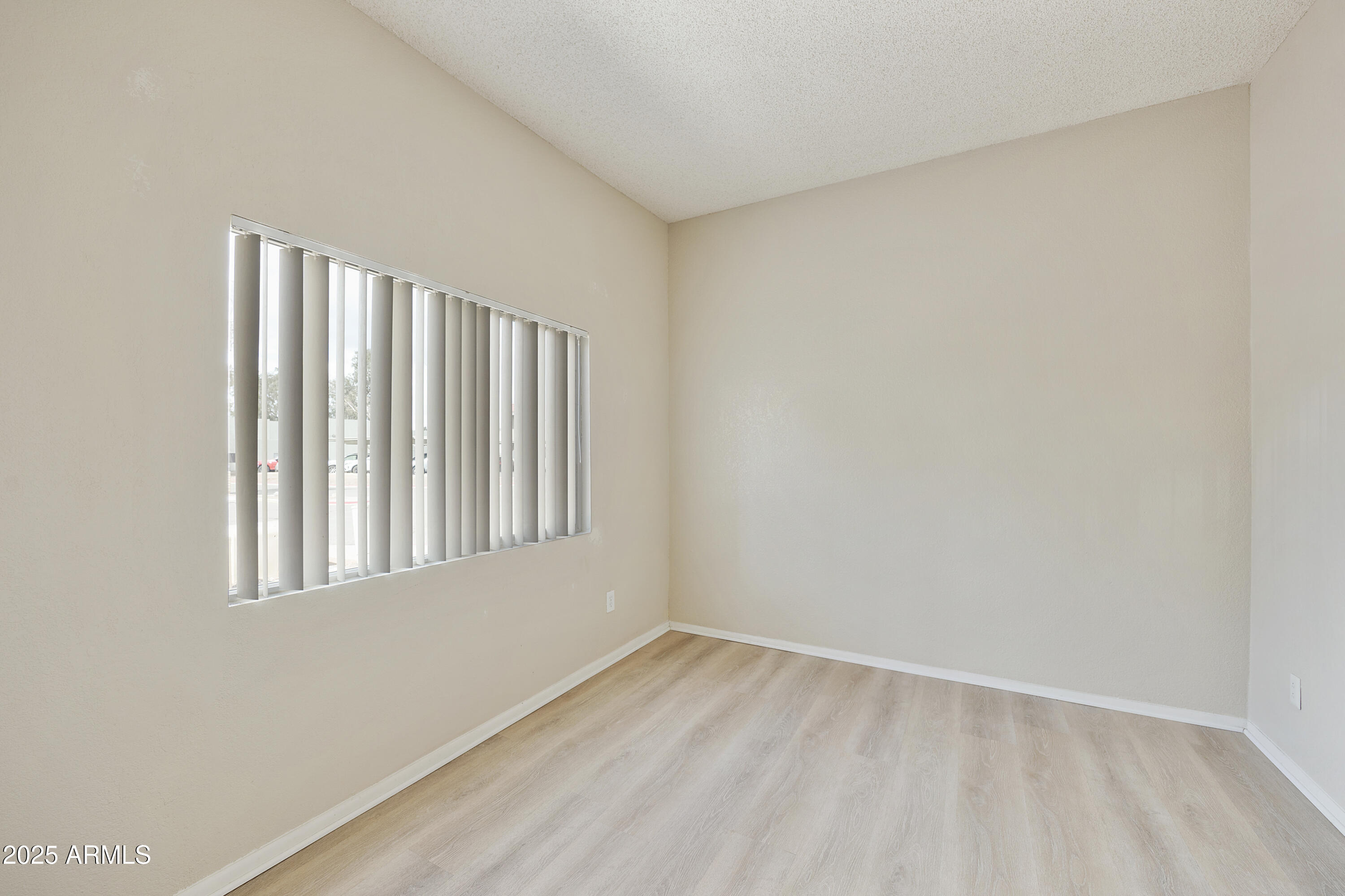 2837 East Marconi Avenue, Unit 102 Phoenix, AZ 85032 - Photo 4 of 8 a view of an empty room with wooden floor and a window