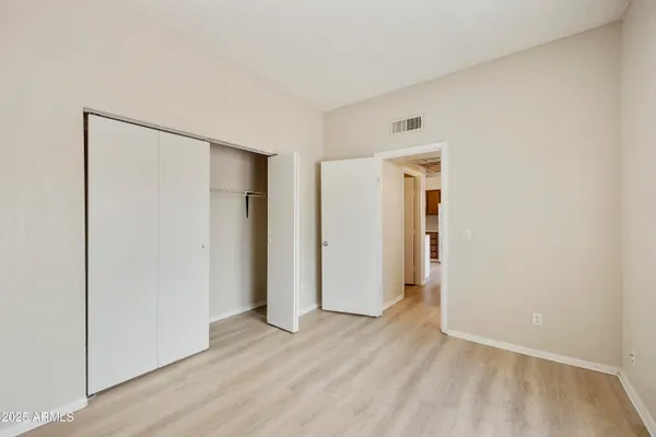 a view of an empty room with wooden floor and closet