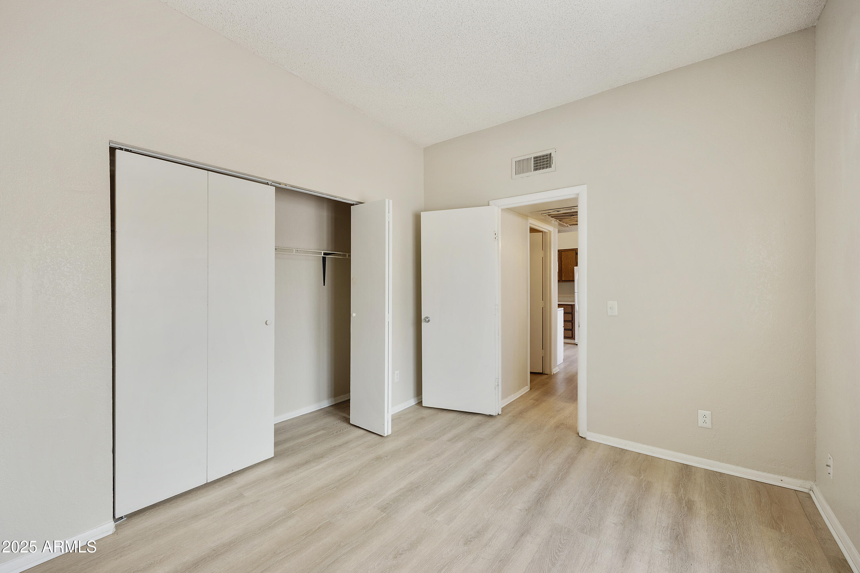 2837 East Marconi Avenue, Unit 102 Phoenix, AZ 85032 - Photo 5 of 8 a view of an empty room with wooden floor and closet