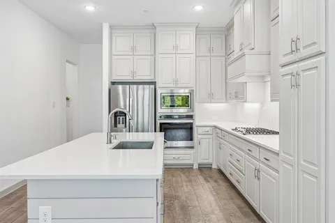 a kitchen with white cabinets and appliances