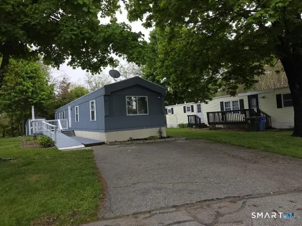 a front view of a house with a garden and trees
