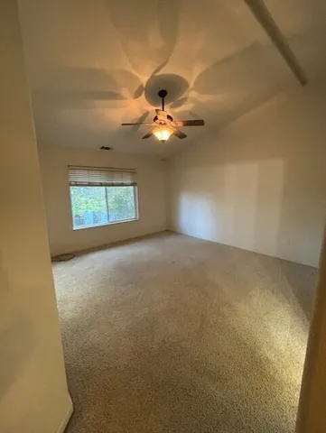 an empty room with a chandelier fan and windows