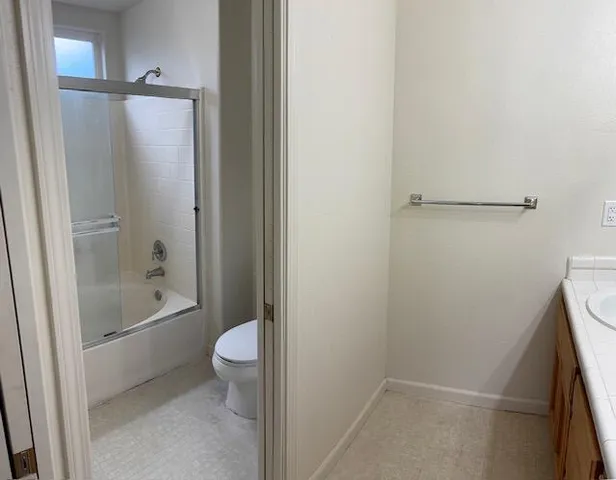 a bathroom with a granite countertop bathtub shower and toilet