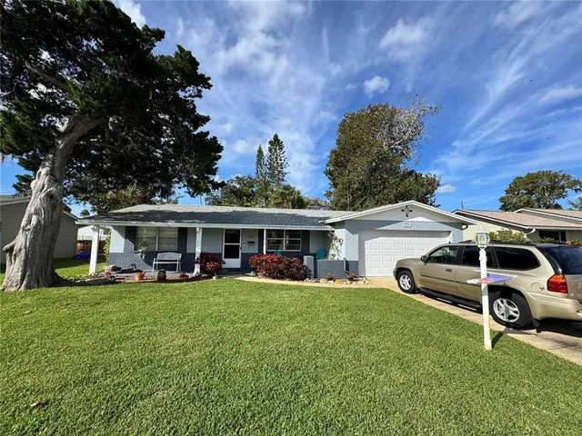 a view of a house with a big yard and large trees