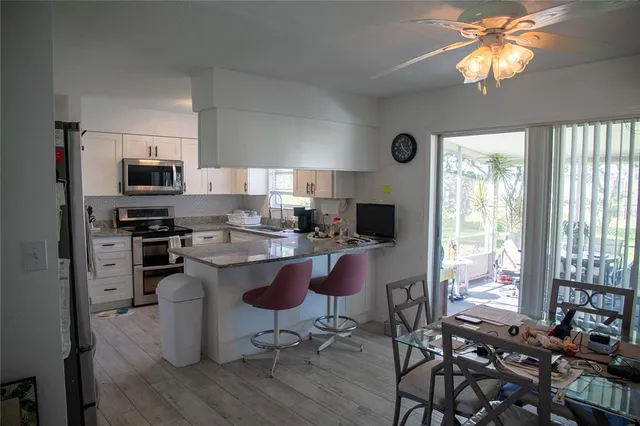 a kitchen with stainless steel appliances granite countertop a stove top oven a sink dishwasher a dining table and chairs with wooden floor