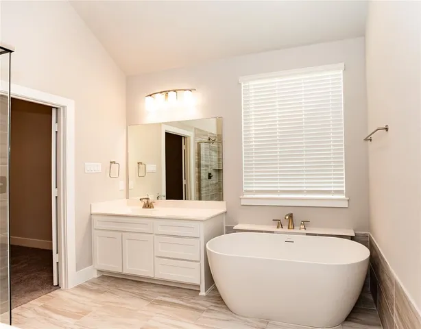 a spacious bathroom with double vanity a window a bathtub and a mirror