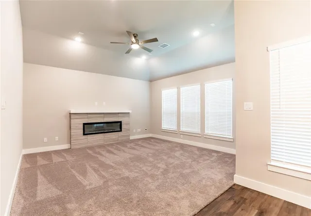 an empty room with windows and ceiling fan