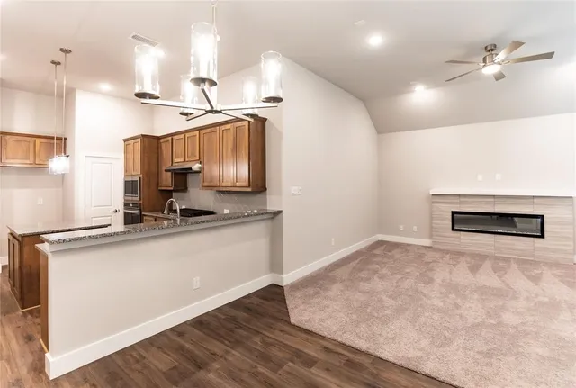 a kitchen with stainless steel appliances granite countertop a sink a stove and a wooden floors