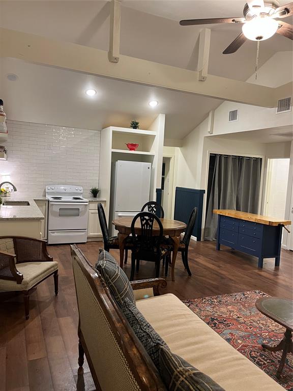 315 Hobson Street Weatherford, TX 76086 - Photo 8 of 24 Open-concept living area featuring vaulted ceilings with exposed beams, wood-finish flooring, recessed lighting, and a kitchen with white subway tile backsplash and granite-finish countertops
