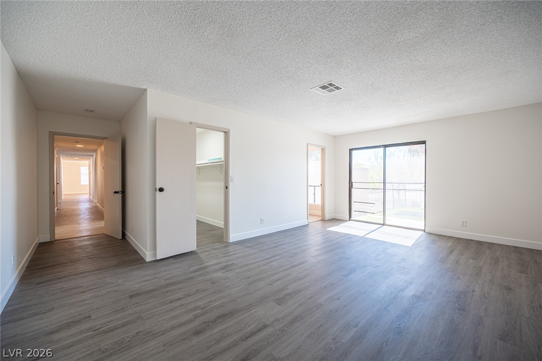 7041 North Decatur Boulevard Las Vegas, NV 89131 - Photo 16 of 33 A spacious room offers ample natural light from sliding glass doors, complementing the elegant gray hardwood-style flooring.