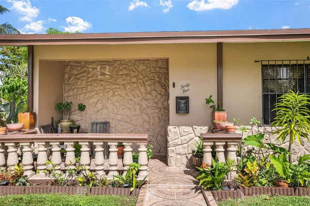 a balcony with table and chairs potted plants