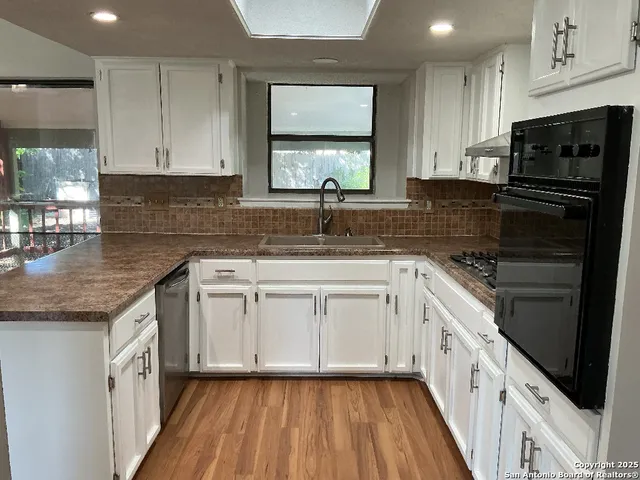 a kitchen with stainless steel appliances granite countertop a sink window and cabinets