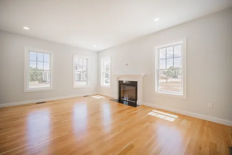 an empty room with windows fireplace and wooden floor