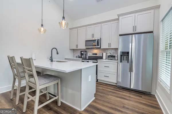 a kitchen with stainless steel appliances a stove a sink dishwasher a refrigerator with white cabinets and wooden floor