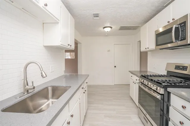 a kitchen with granite countertop a sink stainless steel appliances and cabinets