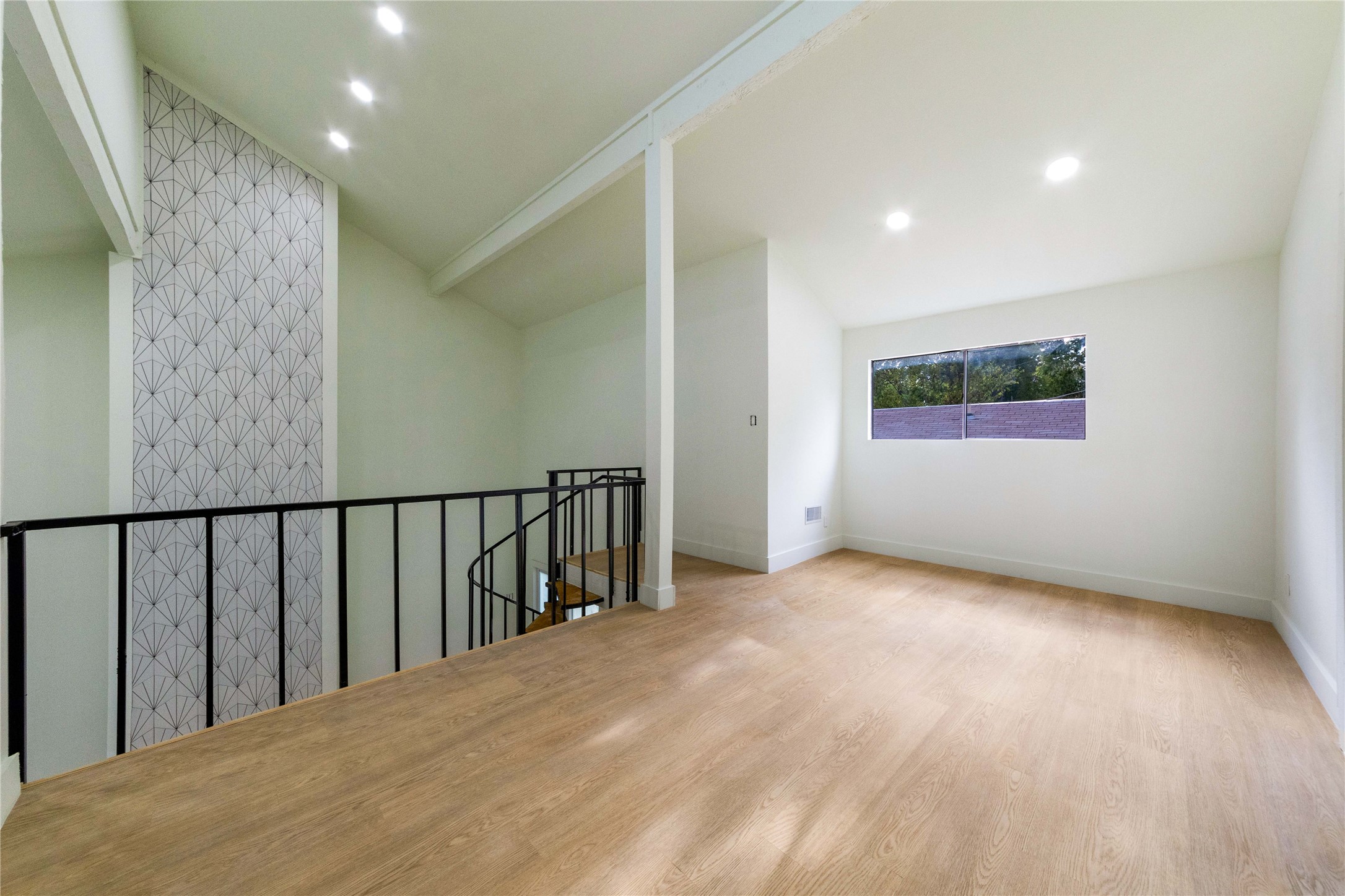 8807 Merion Circle Austin, TX 78754 - Photo 16 of 18 Natural light illuminates this versatile loft space, showcasing light hardwood floors and a modern patterned accent wall.