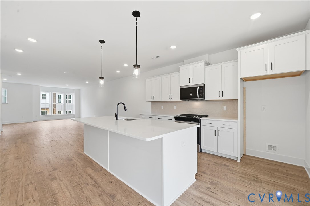 12049 Flowering Lavender Loop Henrico, VA 23233 - Photo 12 of 29 a kitchen with stainless steel appliances granite countertop a sink a stove a refrigerator and white cabinets with wooden floor