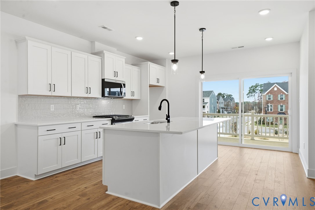 12049 Flowering Lavender Loop Henrico, VA 23233 - Photo 3 of 29 a kitchen with kitchen island granite countertop a stove a sink a center island a refrigerator and a wooden floor