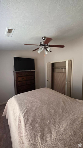 1330 North Dixie Downs Road, Unit 72 St. George, UT 84770 - Photo 12 of 21 Bedroom with a closet, ceiling fan, a textured ceiling, and dark colored carpet