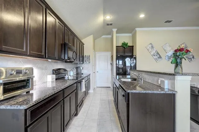 a kitchen with granite countertop stainless steel appliances a sink stove top oven and cabinets