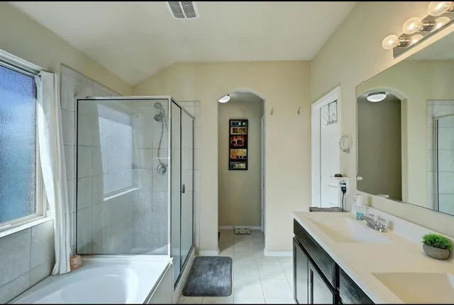 a spacious bathroom with a double vanity sink a mirror and a bathtub