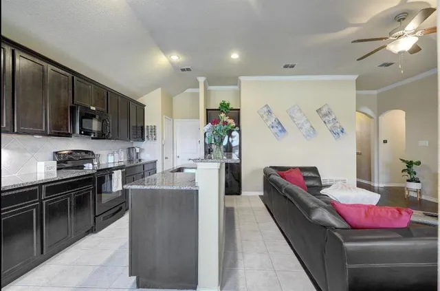 a living room with stainless steel appliances kitchen island granite countertop furniture and a view of kitchen