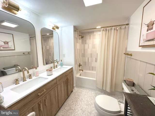 a bathroom with a double vanity sink toilet mirror and bathtub