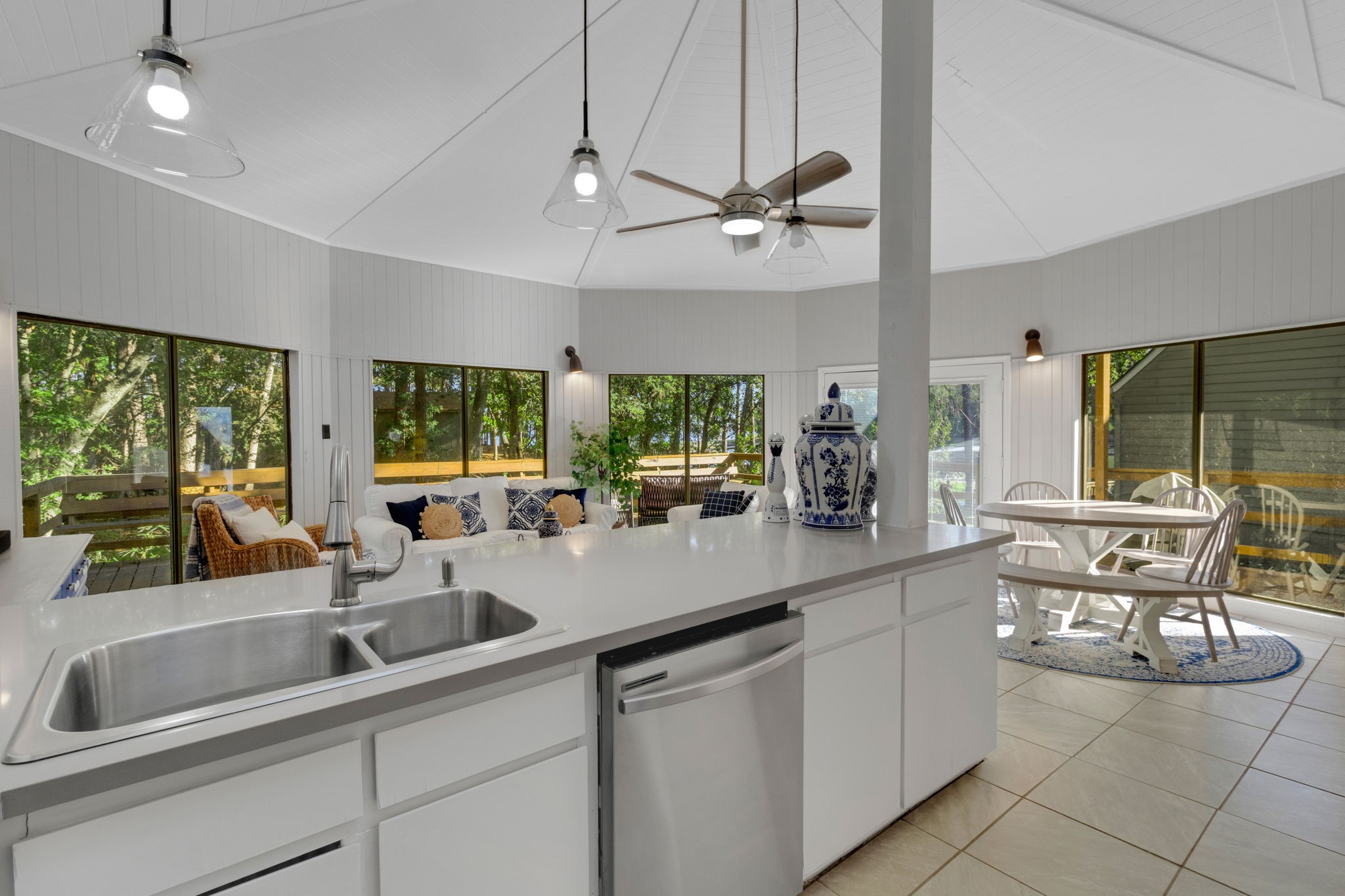 90 Harbour Lane Coldspring, TX 77331 - Photo 6 of 40 Modern kitchen layout featuring quartz countertops, stainless dishwasher, and a panoramic view of the wooded backyard and view of the water just through the trees.