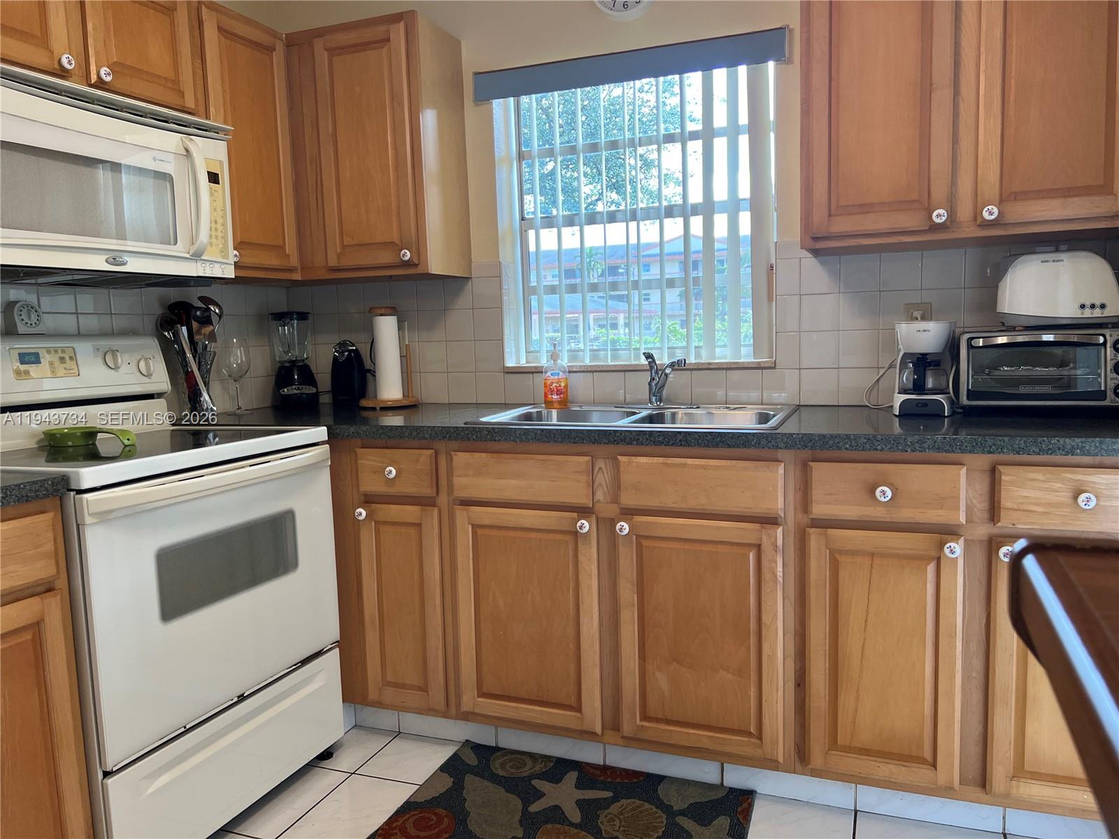 5300 Washington Street, Unit G123 Hollywood, FL 33021 - Photo 10 of 12 a kitchen with granite countertop a sink cabinets stainless steel appliances and a window