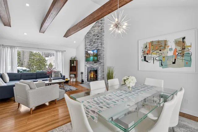 a kitchen with stainless steel appliances a sink a stove a refrigerator a sink a dining table and chairs with wooden floor