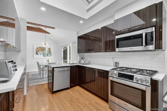 a kitchen with stainless steel appliances granite countertop a stove top oven a sink dishwasher and a microwave oven with large cabinets